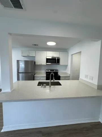 a large white kitchen with kitchen island stainless steel appliances and a counter top space