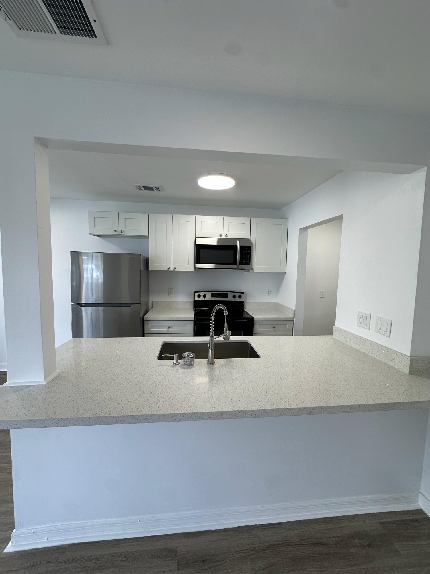 a large white kitchen with kitchen island stainless steel appliances and a counter top space