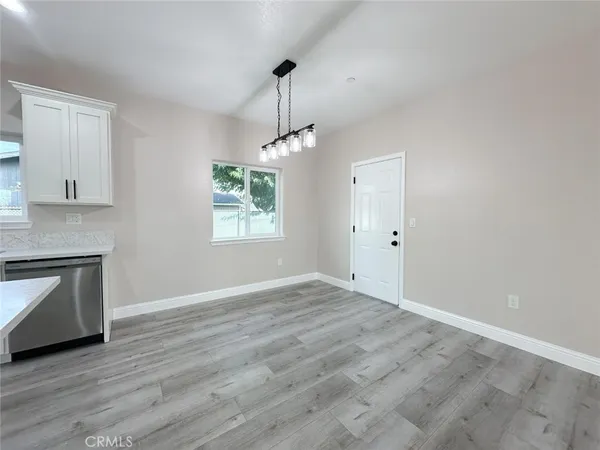 a view of an empty room with window and wooden floor