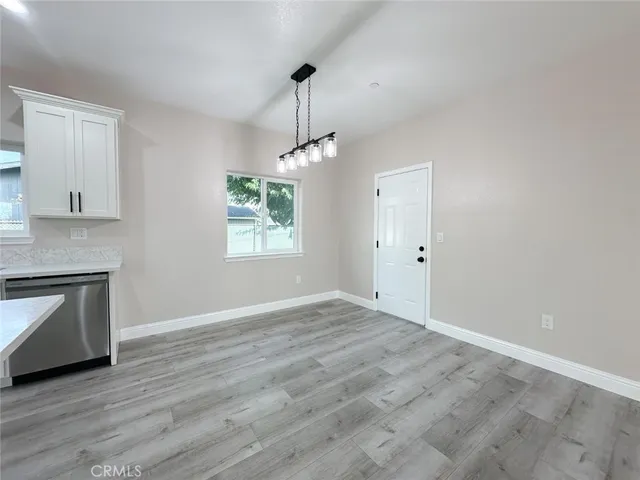 a view of an empty room with window and wooden floor