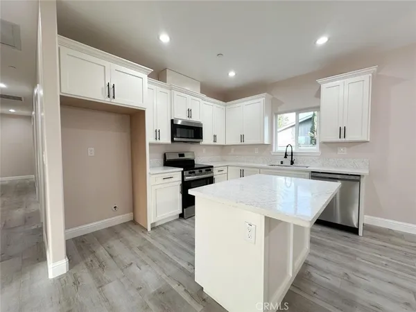 a kitchen with a sink a counter top space stainless steel appliances and cabinets