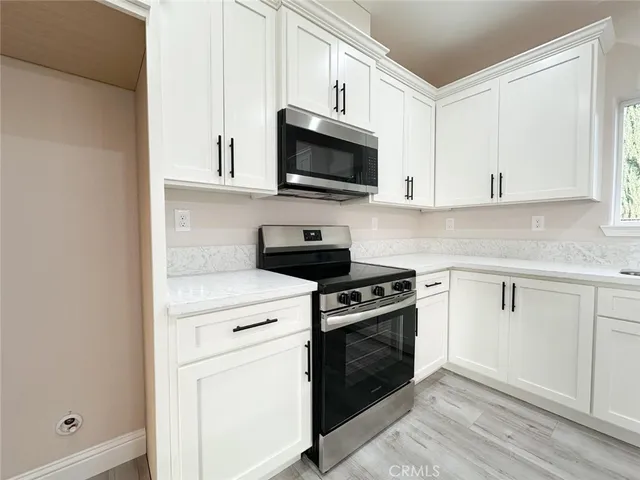 a kitchen with white cabinets and stainless steel appliances