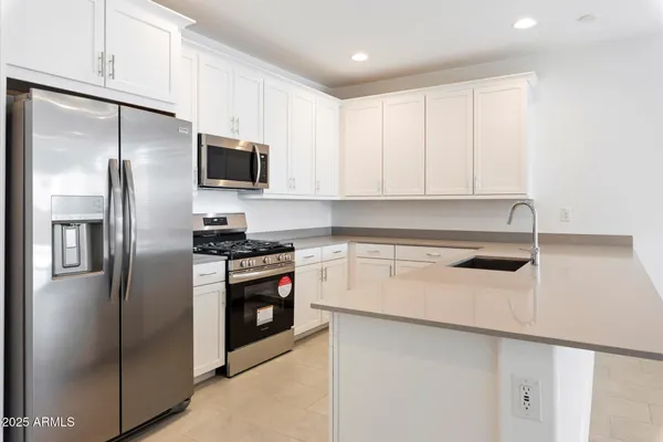 a kitchen with stainless steel appliances granite countertop a stove a refrigerator a microwave and white cabinets