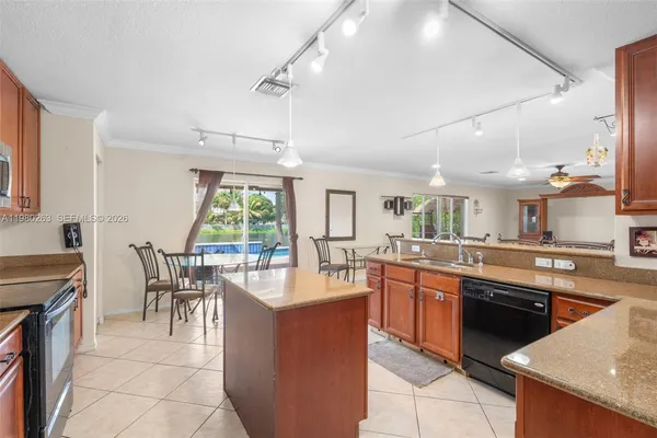 a dining hall with stainless steel appliances granite countertop a stove top oven a sink dishwasher a dining table and chairs with wooden floor