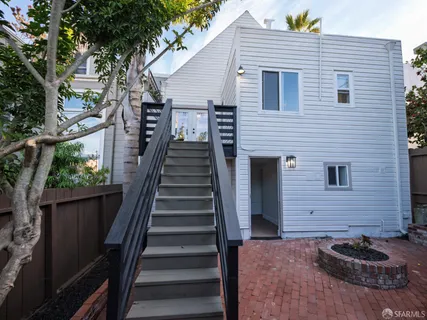 a view of a house with wooden stairs and a large tree