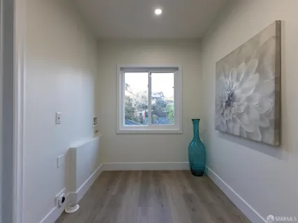 a view of hallway with window and wooden floor