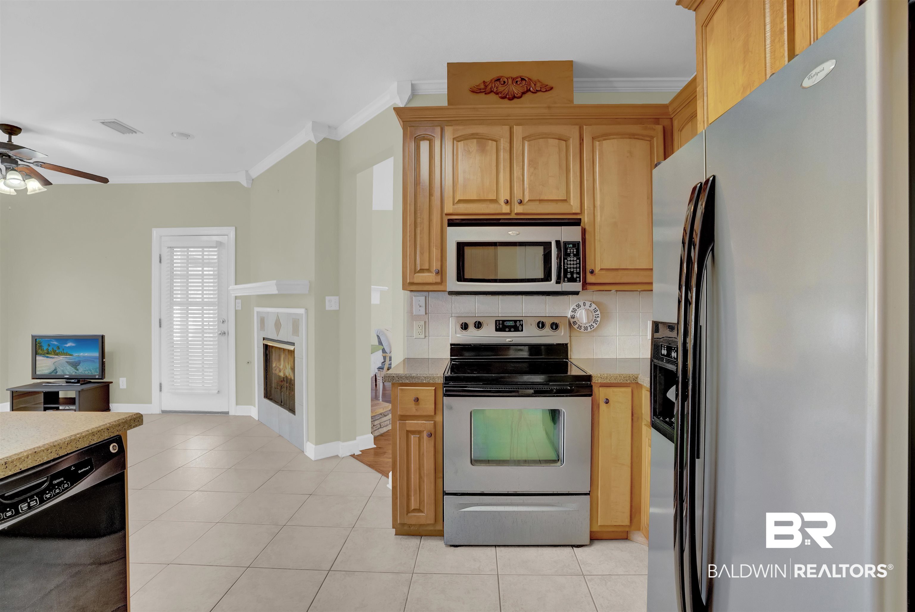 100 Conti Court Fairhope, AL 36532 - Photo 22 of 54 Kitchen featuring ceiling fan, tasteful backsplash, appliances with stainless steel finishes, light tile patterned floors, and ornamental molding