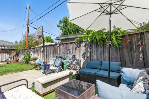 a view of a backyard with couches potted plants and wooden fence