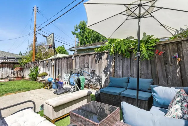 a view of a backyard with couches potted plants and wooden fence