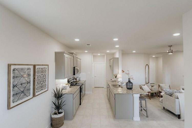 1104 Alexander Street Trenton, TX 75490 - Photo 18 of 18 Kitchen featuring black / electric stove, gray cabinets, a breakfast bar, open floor plan, and light stone countertops