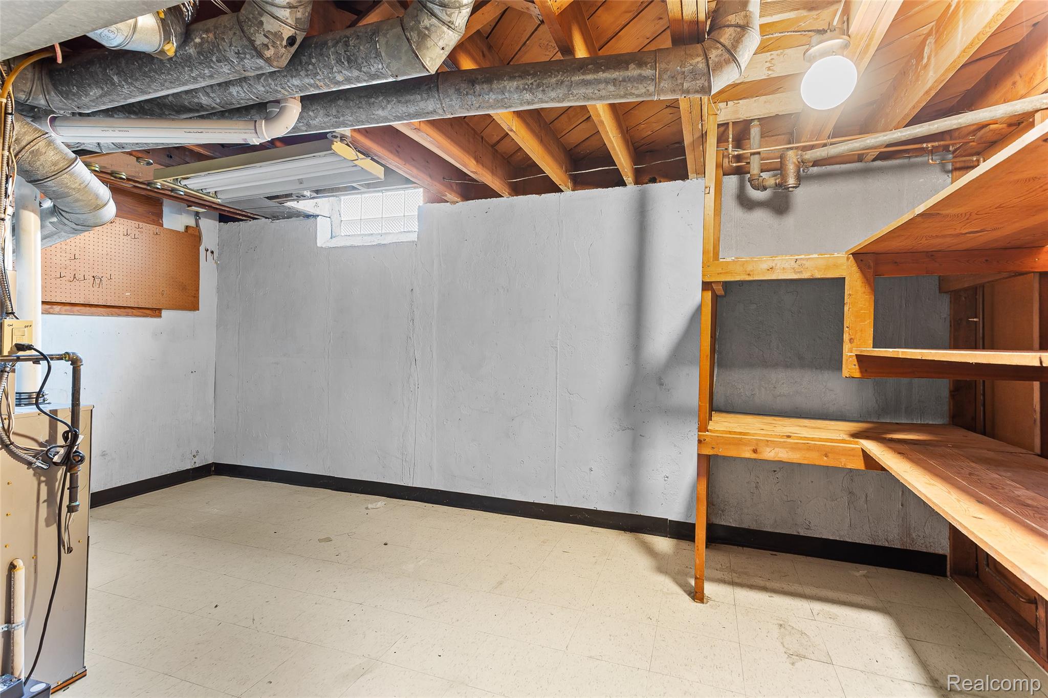 2345 Middlefield Road Trenton, MI 48183 - Photo 31 of 42 Unfinished lower level featuring concrete walls, exposed ceiling joists, and built-in wood shelving