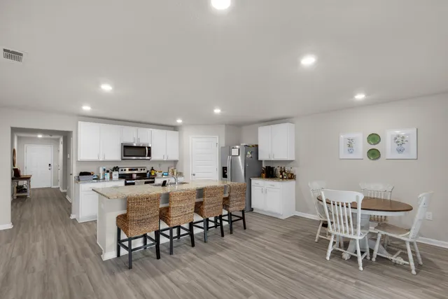 a kitchen with stainless steel appliances a dining table chairs and wooden floor