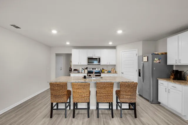 a kitchen with a dining table chairs refrigerator and microwave