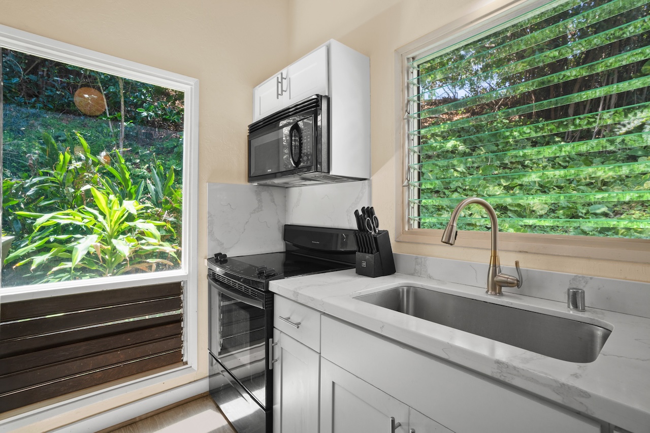 2330 Ho'ohu Road, Unit 27 Koloa, HI 96756 - Photo 13 of 30 a kitchen with a sink and a large window with stainless steel appliances