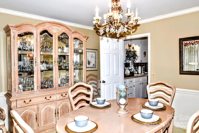 a view of a dining room with furniture a chandelier and large windows