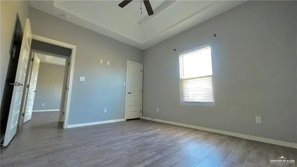 a view of an empty room with a window and wooden floor