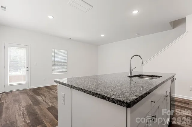 a kitchen with granite countertop a sink and white cabinets