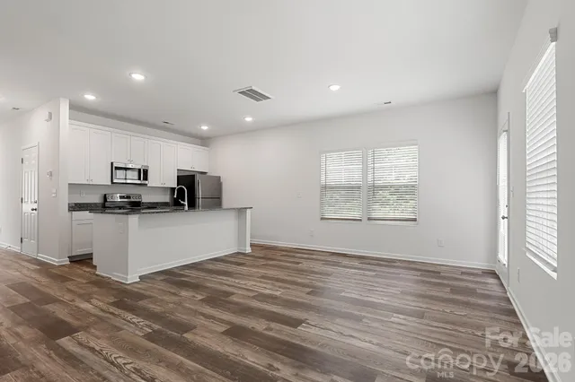 a kitchen with stainless steel appliances kitchen island a sink a stove a microwave and white cabinets