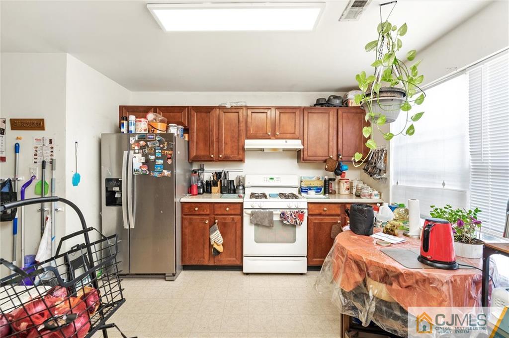 35 Rojewski Way Sayreville, NJ 08859 - Photo 5 of 23 a kitchen with stainless steel appliances granite countertop a stove a refrigerator and a dining table with wooden floor