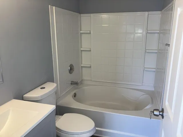 a white bath tub sitting next to a white toilet and a sink