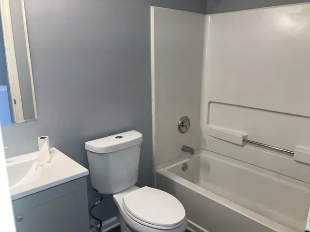 a white toilet and tub next to a white cabinet