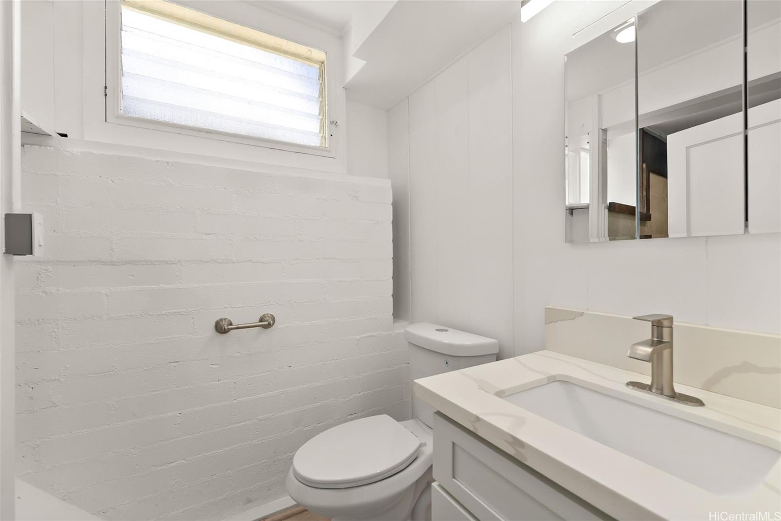 2811 Henry Street Honolulu, HI 96817 - Photo 19 of 25 Fresh and pristine, this bright white bathroom features a modern vanity and classic jalousie windows to let in the cool island breeze.