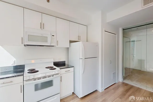 a kitchen with a refrigerator stove and white cabinets