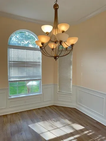 a view of a livingroom with a chandelier and wooden floor