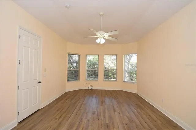 a view of a room with wooden floor a ceiling fan and a window
