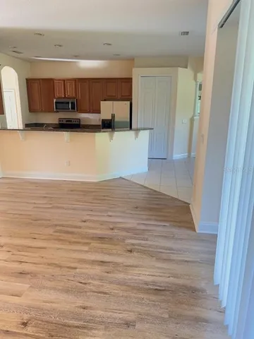 a view of kitchen and empty room with wooden floor