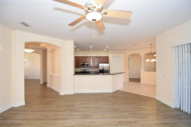 a view of an empty room and kitchen with wooden floor and a fireplace