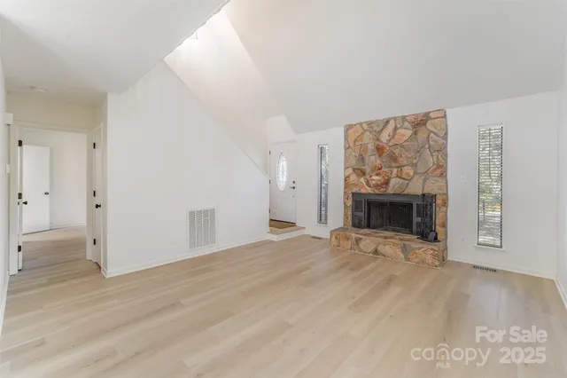 a view of empty room with wooden floor and fireplace