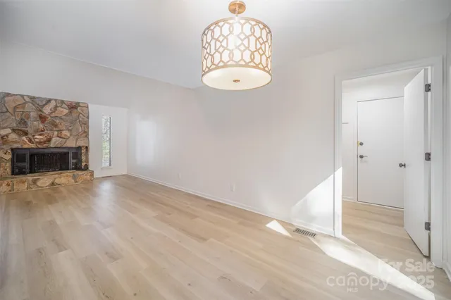 an empty room with wooden floor a fireplace and windows