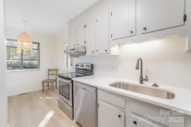 a kitchen with stainless steel appliances granite countertop a sink a stove and cabinets