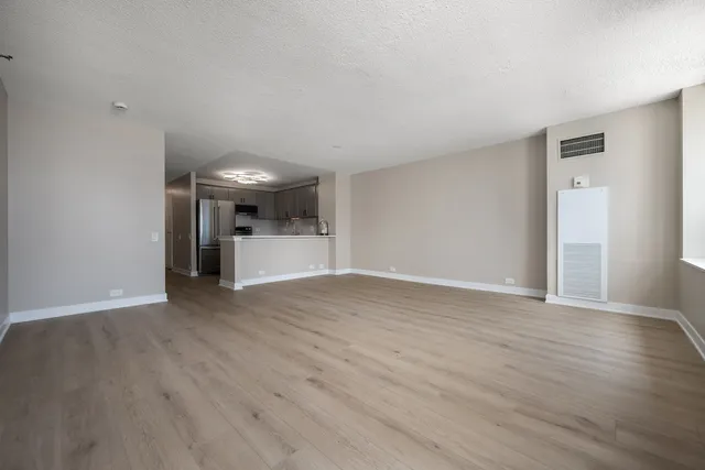 a view of a kitchen and an empty room with wooden floor