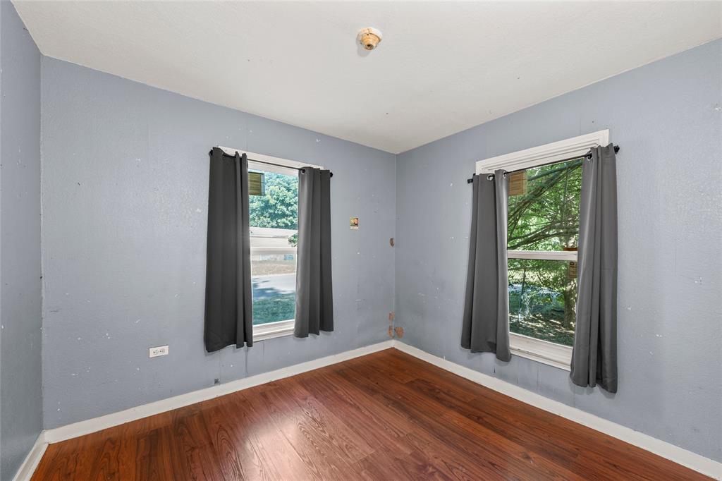 2225 Mitchell Avenue Waco, TX 76708 - Photo 9 of 16 Interior room featuring wood-finish flooring, light blue wall paint, and two windows with white trim