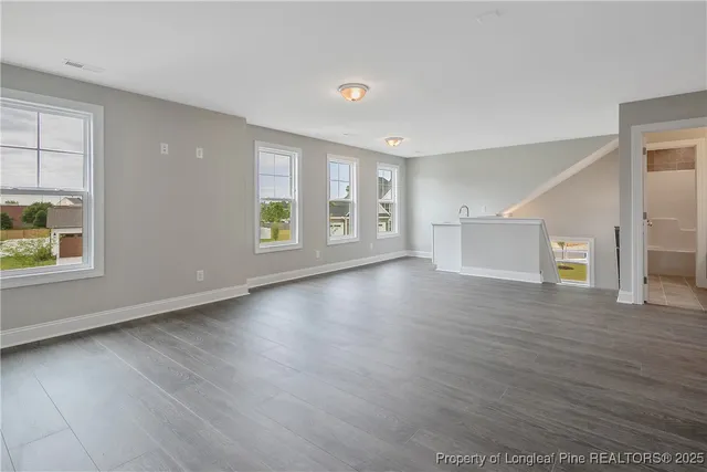 a view of an empty room with wooden floor and windows