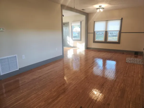 a view of empty room with wooden floor and fan