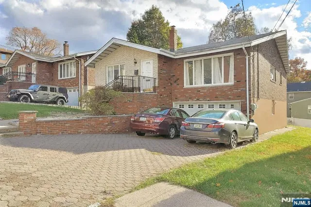 a view of a white house and a yard with a cars parked in front of a house