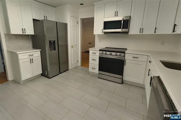 a kitchen with stainless steel appliances a refrigerator stove and white cabinets