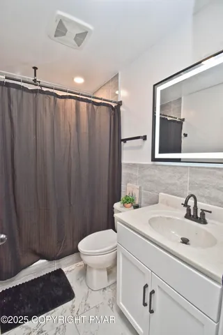 a bathroom with a sink a toilet a mirror and shower