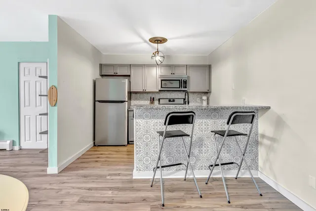 a kitchen with stainless steel appliances kitchen island granite countertop a refrigerator a stove a sink dishwasher and white countertops with wooden floor