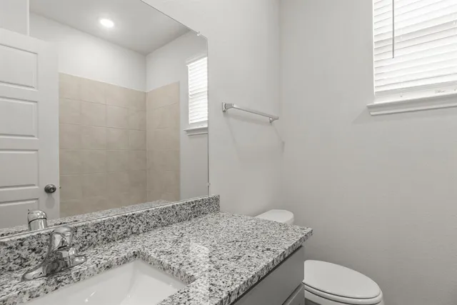 a bathroom with a granite countertop sink toilet and mirror