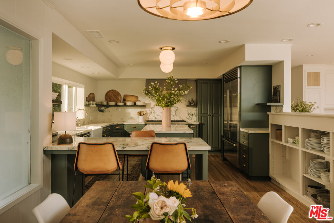 2610 Mandeville Canyon Road Los Angeles, CA 90049 - Photo 12 of 32 a kitchen with stainless steel appliances a dining table and chairs