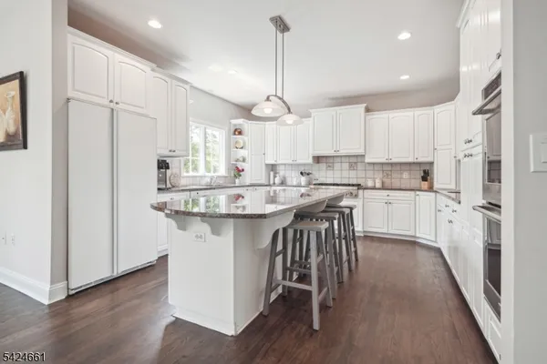 a kitchen with kitchen island granite countertop a sink cabinets and wooden floor