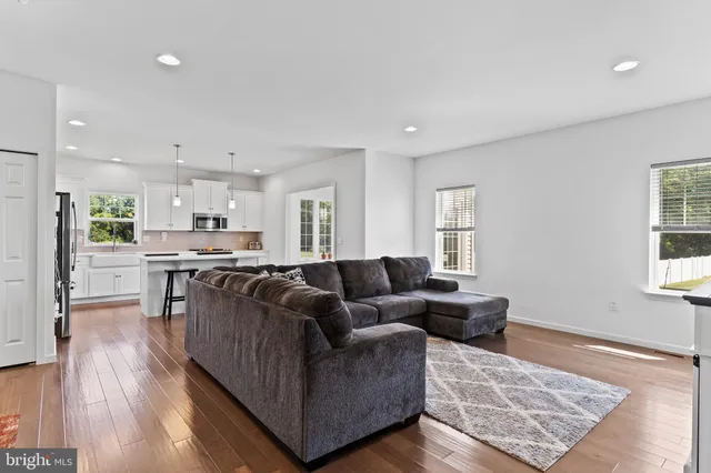a living room with stainless steel appliances furniture and wooden floor
