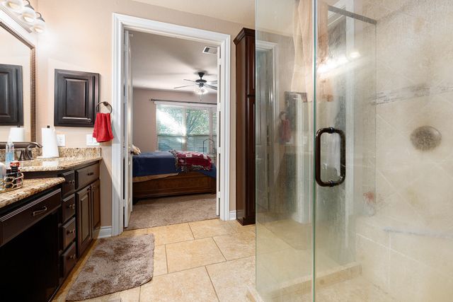 a en suite bathroom with a granite countertop shower sink and mirror