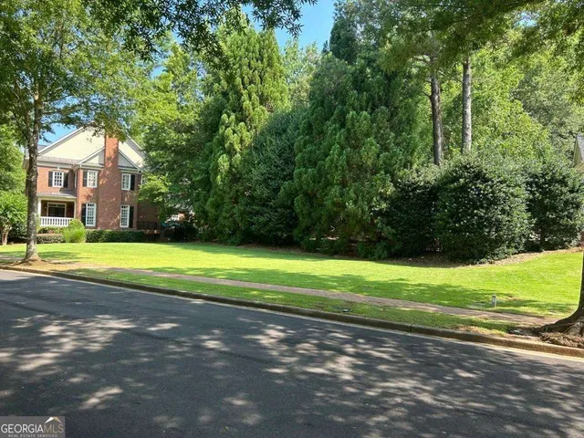 a view of a house with a yard and a large tree