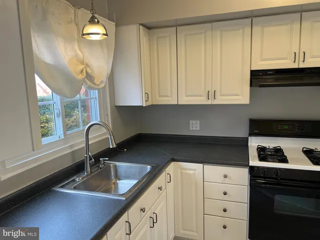 a kitchen with granite countertop a sink a stove and cabinets
