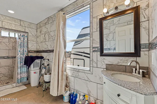 a bathroom with a granite countertop sink a mirror and a shower